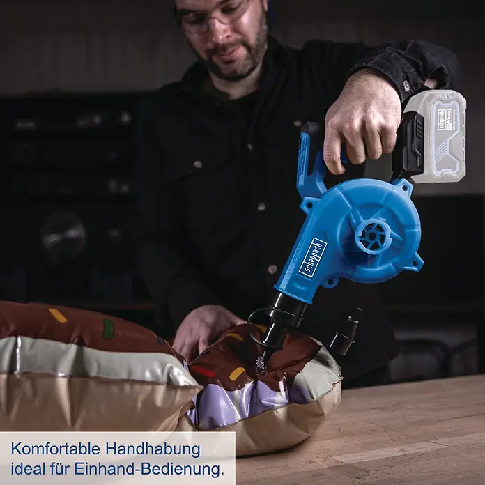 Scheppach IXES 20V Akku-Gebläse C-WBL180-X - 20 V, Ohne Akku - Eine Person bläst ein braunes Objekt mit einem blauen Scheppach Akku-Gebläse/Pumpe auf, komfortabel mit einer Hand bedienbar.