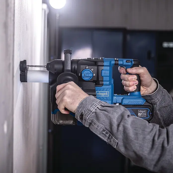 Scheppach IXES 20V Akku-Kombihammer - 20 V, Ohne Akku, 2,8 J - Eine Person bohrt mit einem blau-schwarzen Scheppach Akku-Bohrhammer in eine helle Wand.
