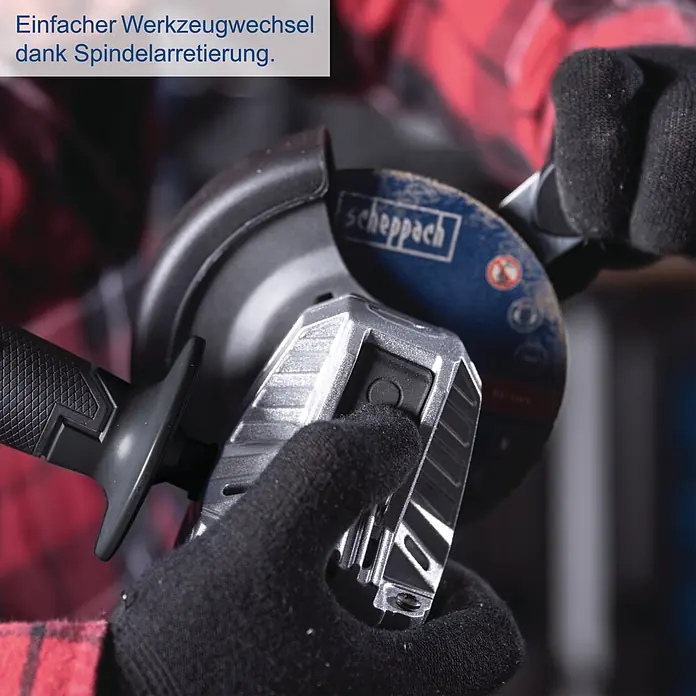 Scheppach IXES 20V Akku-Winkelschleifer BC-AG125P-X - 20 V, Ohne Akku, 7.000 U/min - 10.000 U/min - Person in Handschuhen drückt die Spindelarretierung einer silber-schwarzen Winkelschleifmaschine mit blauer Trennscheibe für einfachen Werkzeugwechsel.