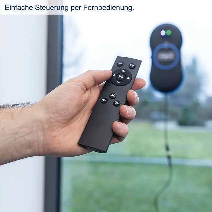 Scheppach Fensterreinigungsroboter WCR72 - Wassertankvolumen Roboter: 35 ml, Saugkraft: 2.800 Pa - Hand hält schwarze Fernbedienung, um einen schwarz-blauen Fensterputzroboter auf einem Fenster im Hintergrund zu steuern.