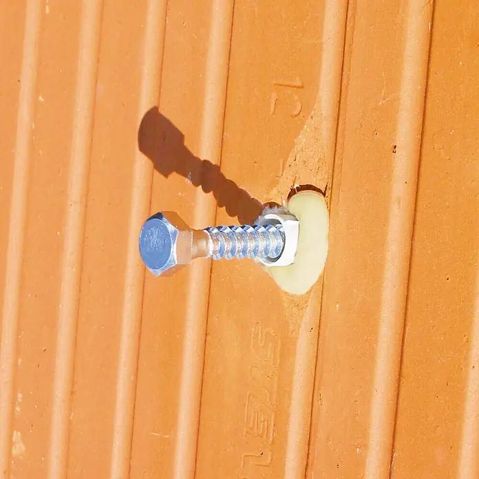 Beko Konstruktionskleber Allcon 10 - 150 ml, Beige - Verzinkte Sechskant-Holzschraube mit Unterlegscheibe und Dichtmittel, in einer gerippten Terrakotta-Fliese befestigt.