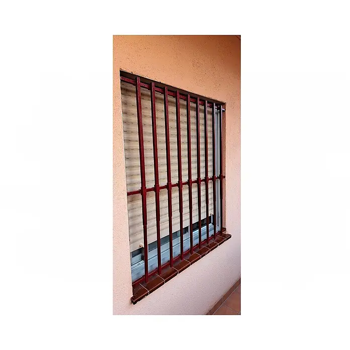 Adaptta Fenstergitter ausziehbar 55×95–100×165 cm, schwarz - Montage Fenstergitter: Fensterrahmenmontage - Dunkelrote Metall-Fenstergitter vor einem beigen Rollladen.