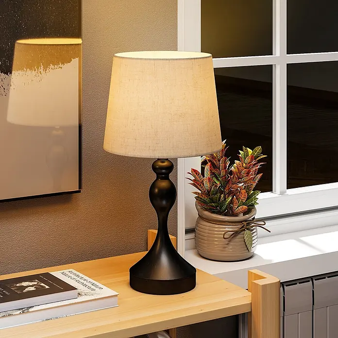 Homcom Tischleuchte - 40 W, L x B x H: 28 x 28 x 54 cm, Schwarz, Cremeweiß, E27 - Schwarze Tischlampe mit beigem Stoffschirm auf einem hellen Holztisch, die warmes Licht spendet.