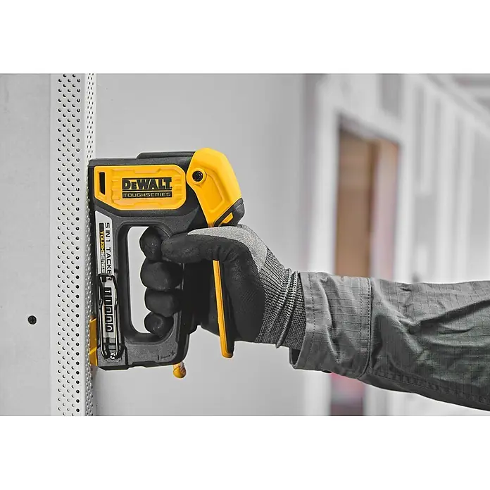 DeWalt Grapadora manual DWHT70510 - Profundidad de grapado: 6 mm - 14 mm - Mano enguantada usando una grapadora DeWalt Toughseries 5-en-1 amarilla y negra para fijar una tira perforada blanca a una superficie.