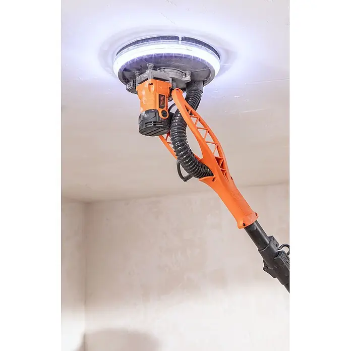 Black+Decker Lijadora de pared y techo BEDW700 - 710 W, Diámetro disco de lija: 225 mm - Lijadora de techo naranja y negra BLACK+DECKER con anillo de luz lijando un techo blanco.