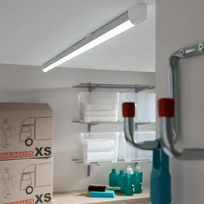 Ritter Leuchten LED-Lichtleiste - L x B x H: 123,3 x 3 x 4 cm, Lichtfarbe: Tageslichtweiß, 20 W, 230 V - Aufnahme einer Deckenleuchte in einem Lagerraum, die für helles Licht sorgt. Regale, Kisten und Reinigungsartikel sind im Hintergrund zu sehen.