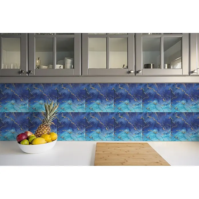 Tulup Wandfliese - Glänzend - Blaue und goldene Küchenrückwandfliesen mit Marmormuster über einer Arbeitsplatte, mit Obstschale und Schneidebrett als Größenvergleich.