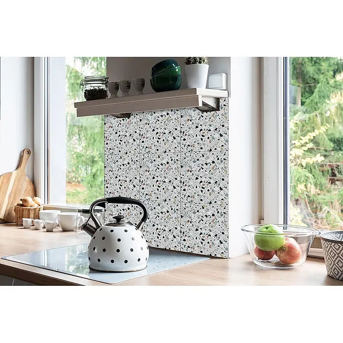 Tulup Wandfliese - Glänzend - Terrazzo-Küchenrückwand mit mehrfarbigen Chips, hinter einem Wasserkocher und unter einem Regal in einer hellen Küche installiert.
