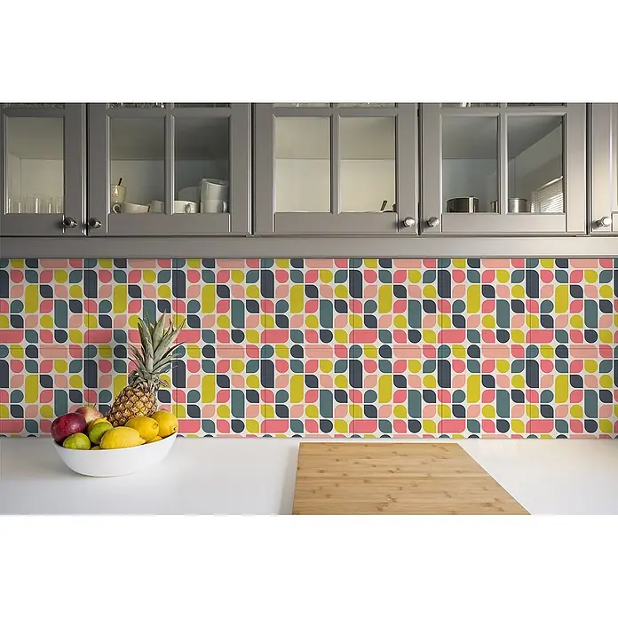 Tulup Wandfliese - Glänzend - Bunter geometrischer Fliesenspiegel in einer Küche mit rosa, gelben und blaugrünen Formen unter grauen Schränken.