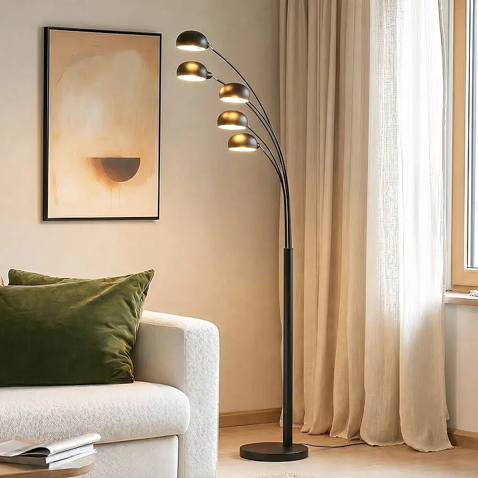 Lindby Stehleuchte Jewa - schwarz, schwarz, E14 - Schwarze Stehlampe aus Metall mit fünf gebogenen Armen und einzelnen Kuppelleuchten, die eine Wohnecke neben einem Sofa beleuchtet.