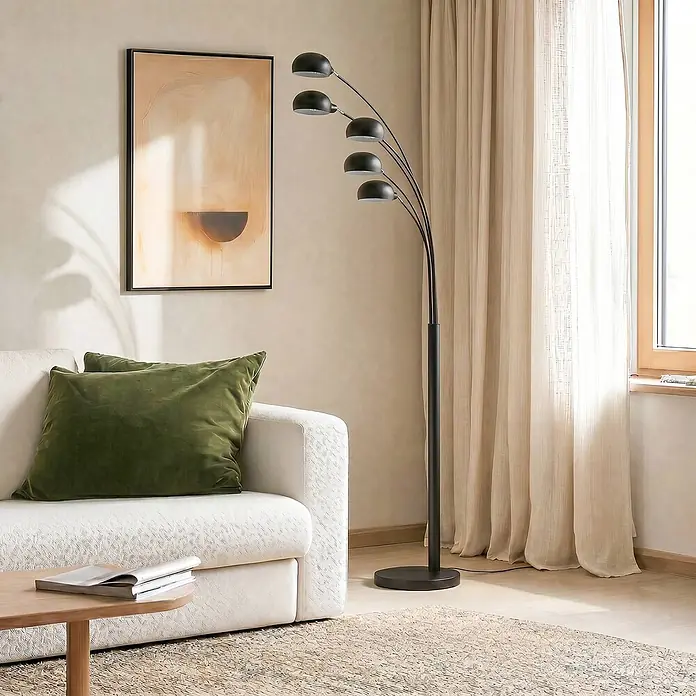 Lindby Stehleuchte Jewa - schwarz, schwarz, E14 - Schwarze Fünfflammen-Bogenstehleuchte beleuchtet modernes Wohnzimmer neben weißem Sofa.