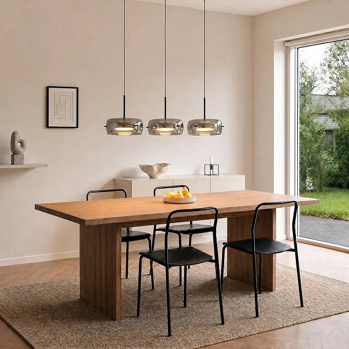 Lucande LED Pendelleuchte in schwarz, dimmbar Hängelampe -  - Drei Hängelampen aus grauem Rauchglas mit schwarzen Aufhängungen, linear über einem Holztisch angeordnet.