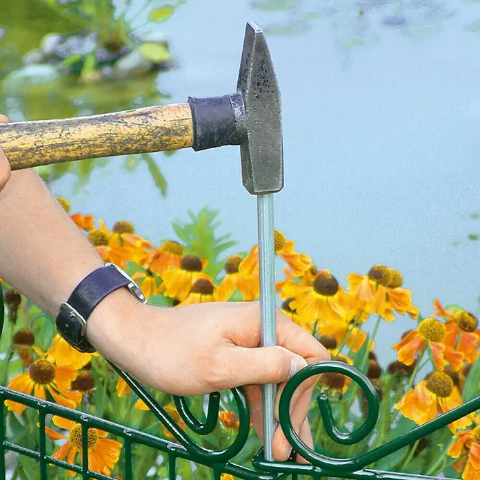Bellissa Teichschutzzaun Ambiente - 76 x 95 cm - Ein Mann befestigt einen grünen Gartenzaun mit einem Hammer und einem Metallstift, um ihn sicher zu installieren und das Gartenprojekt abzuschließen.