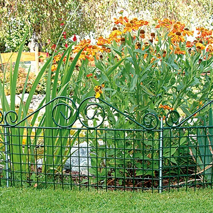 Bellissa Teichschutzzaun Ambiente - 76 x 44 cm - Ein grüner Gartenzaun mit dekorativen Spiralen schützt ein Blumenbeet mit orangen Blüten vor einem Rasen.