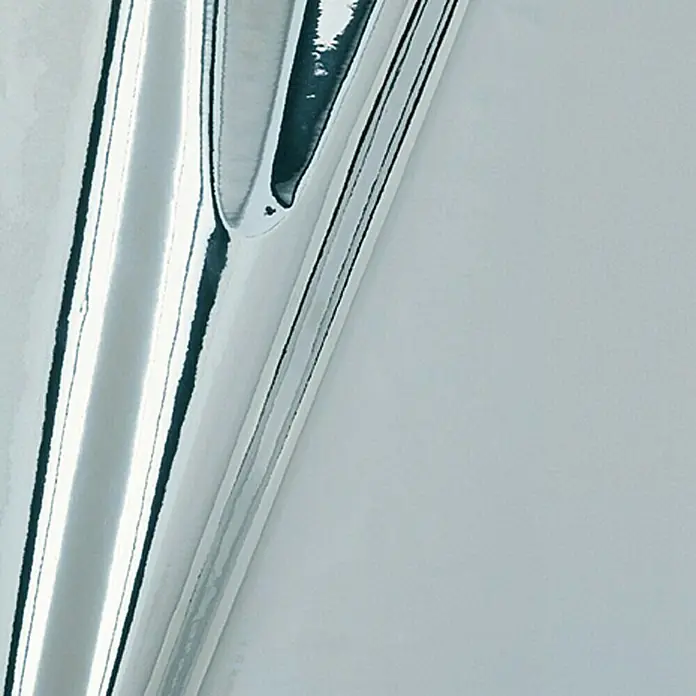 D-c-fix Metalleffektfolie Metallic Hochglanz - 150 x 45 cm, Silber, Selbstklebend - Detailaufnahme einer Rolle glänzender, silberner Geschenkfolie, die auf einem hellen Untergrund liegt und Lichtreflexionen zeigt.