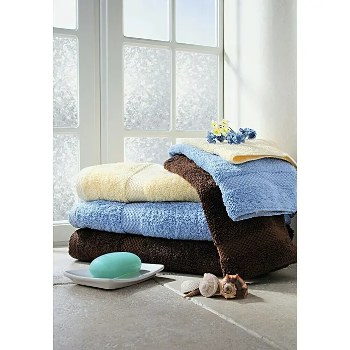 D-c-fix Static Glasfolie Splinter - 150 x 90 cm, Transluzent, Statisch haftend - Ordentlich gestapelte Handtücher in Gelb-, Blau- und Brauntönen mit Seife und Muscheln im Badezimmer.