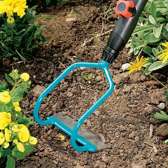 Gardena Combisystem Bügelzughacke - Arbeitsbreite: 12 cm, Edelstahl - Eine blaue Pendelhacke von Gardena steht in einem Beet mit gelben Blumen und lockert den Boden für die Gartenarbeit.