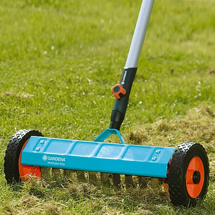 Gardena Combisystem Vertikutierboy - Arbeitsbreite: 32 cm, Geeignet für: Moos- und Rasenfilzentfernung - Gardena Vertikutierboy Handvertikutierer für die Rasenpflege mit Rädern und Griff auf einer Rasenfläche.