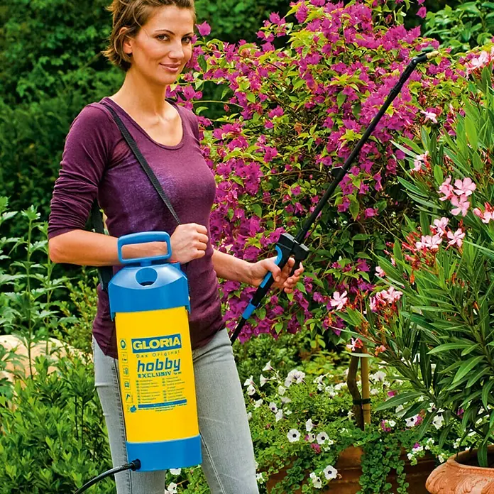 Gloria Sulfatadora Hobby Exclusiv - Presión de funcionamiento: 3 bar, Plástico - Mujer regando flores con un pulverizador a presión Gloria Hobby azul y amarillo. El pulverizador tiene una correa.