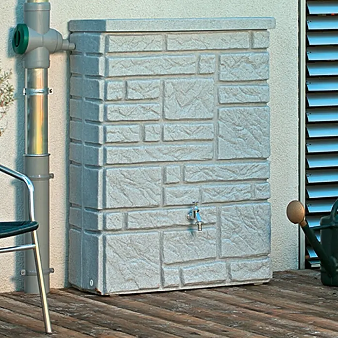 Arves Regenspeicher Maurano - 300 l, Granitfarben, 1 Stk. - Grauer Regenwassertank mit Steinmuster und einem Wasserhahn, verbunden mit einem Fallrohr, der auf einer Holzterrasse steht.