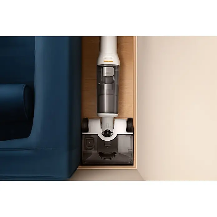 Roborock Akku-Nass-Trockensauger F25 RT Gen 2 - Saugkraft: 20.000 Pa, Akkulaufzeit: 22 min - 38 min, Wassertankvolumen: 870 ml - Draufsicht auf einen weißen, grauen und schwarzen Stielstaubsauger zwischen einem blauen Sofa und einer hellen Wand.