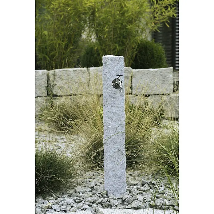 Arves Wasserzapfstelle Natura - Granitfarben, Höhe: 98 cm - Nahaufnahme einer stilvollen Wasserstelle mit Granitsäule und chromfarbenem Wasserhahn in einem Garten.