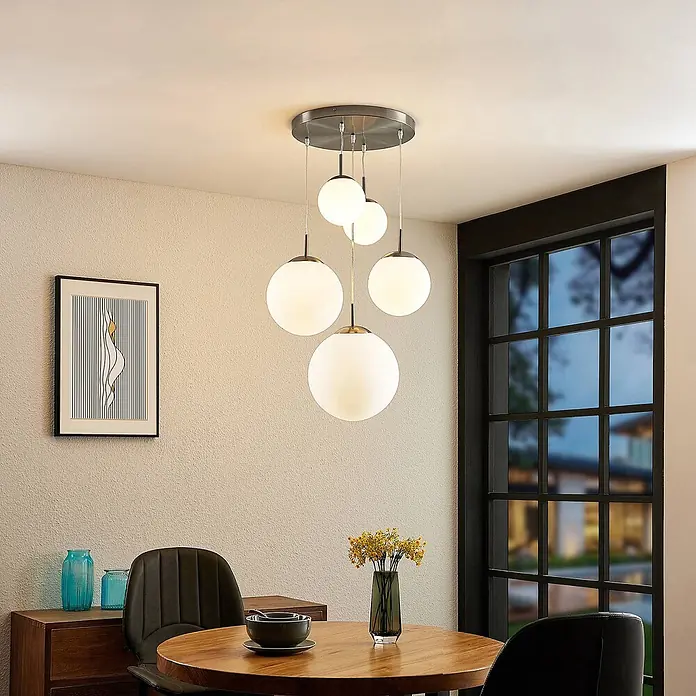 Lindby Pendelleuchte Heleska - weiß / opal, nickel matt, opalweiß, E27 - Eine moderne Pendelleuchte mit fünf weißen Glaskugeln, die von einer gebürsteten Metallbasis herabhängen und einen Essbereich beleuchten.