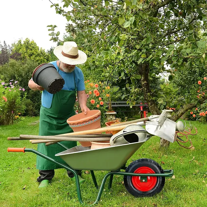 Schubkarrenrad 2er Set luftbereift mit Achse Ø 390 mm Schwarz 200kg -  - Ein Mann im Garten legt Töpfe in eine grüne Schubkarre voller Gartengeräte.