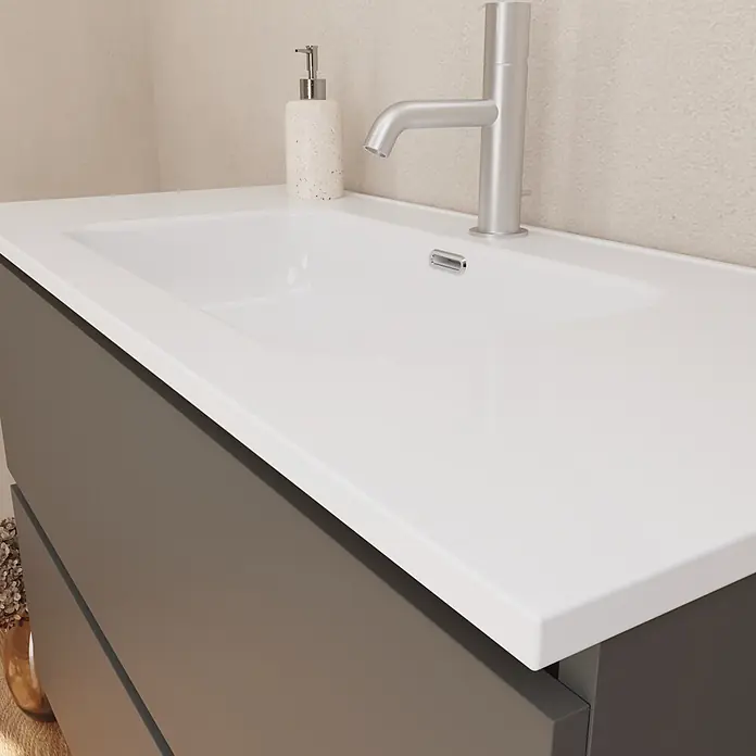 Lavabo empotrado Nairobi - 101 x 46 cm, Orificios para grifo: Medio, Sin desbordamiento, Blanco, Brillante - Mueble de baño moderno con lavabo blanco integrado, grifo plateado y mueble bajo gris oscuro. Un dispensador de jabón con aspecto de piedra está en la encimera.