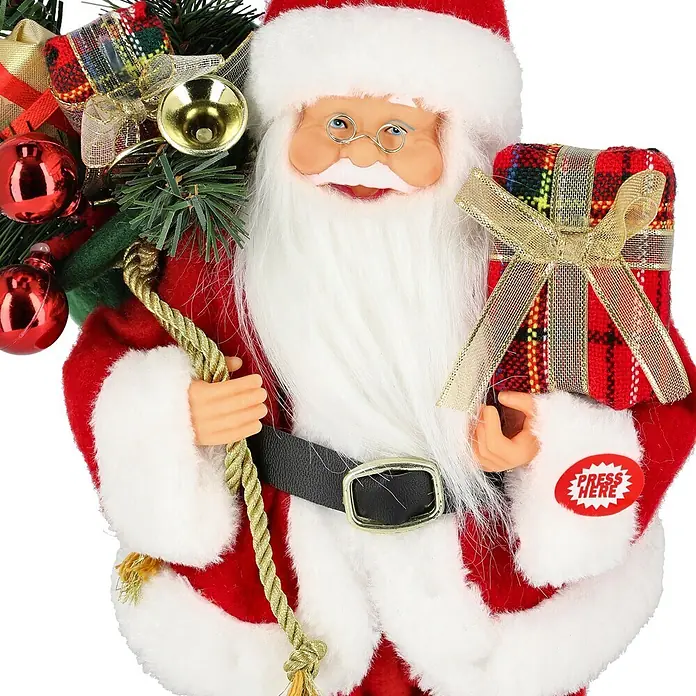 Mica Decorations Dekofigur Holly Jolly Christmas - Polyester - Lächelnde Weihnachtsmannfigur im roten Anzug mit weißem Besatz, hält ein kariertes Geschenk mit „PRESS HERE“-Knopf und goldenem Seil, dekoriert mit festlichem Grünzeug.