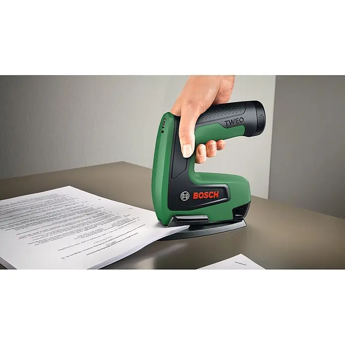 Bosch Akku-Tacker Tweo - 4 V, 1 Akku, 2 Ah, Klammertiefe: 4 mm - 10 mm - Eine Hand bedient einen grün-schwarzen Bosch TWEQ Hefter auf einem Stapel weißer Papiere.