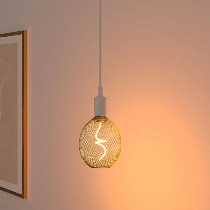 Paulmann LED-Lampe Globe Bernstein - E27, Warmweiß, 180 lm, 4 W - Beleuchtete LED-Filamentlampe mit goldenem Drahtgeflecht, an weißer Schnur hängend in einem warmen Raum.