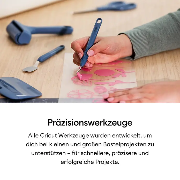 Cricut Plotter-Werkzeug XL-Rakel - Geeignet für: Aufkleber, Blau - Eine Hand nutzt ein blaues Cricut Entgitterwerkzeug, um überschüssiges Material von einem pinken Bastelmotiv zu entfernen, weitere Werkzeuge sind sichtbar.