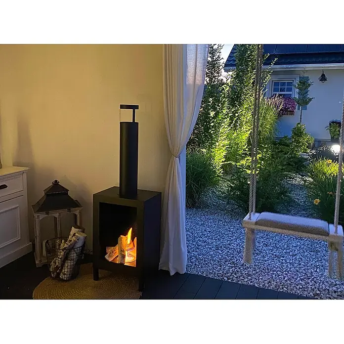 Bysil Kaminofen - Material Verkleidung: Stahl, Schwarz - Schwarzer Outdoor-Kamin mit Kunstholz und Flammen-Effekt, spendet Wärme auf einer Terrasse.