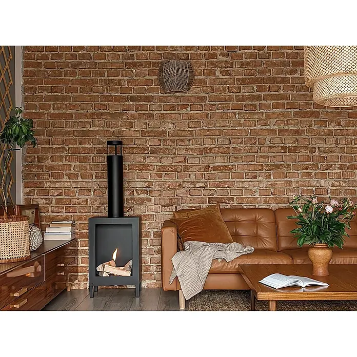 Bysil Kaminofen - Material Verkleidung: Stahl, Schwarz - Schwarzer Bio-Kamin mit Flamme und Holzscheiten, im Wohnzimmer neben einem braunen Ledersofa stehend.
