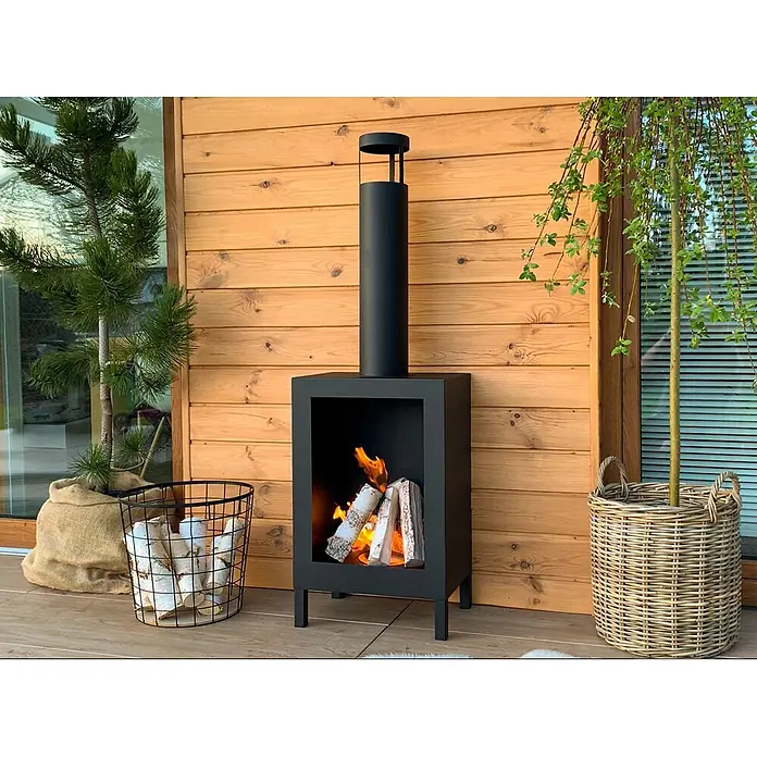 Bysil Kaminofen - Material Verkleidung: Stahl, Schwarz - Schwarzer Metall-Außenkamin mit hohem Schornstein, aktiv brennendem Holz, auf einer Holzterrasse platziert.