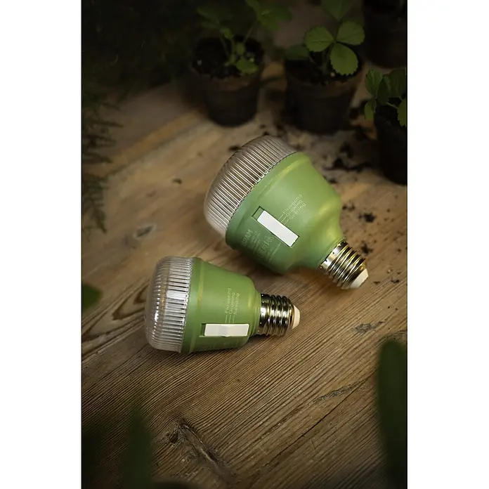 Ledvance Bombillas LED Star Grow - E27, No regulable, Multicolor, 650 lm, 20 W - Dos luces de crecimiento verdes sobre madera, junto a plantas en macetas. Una etiqueta dice "Flowering Growing Seeding".