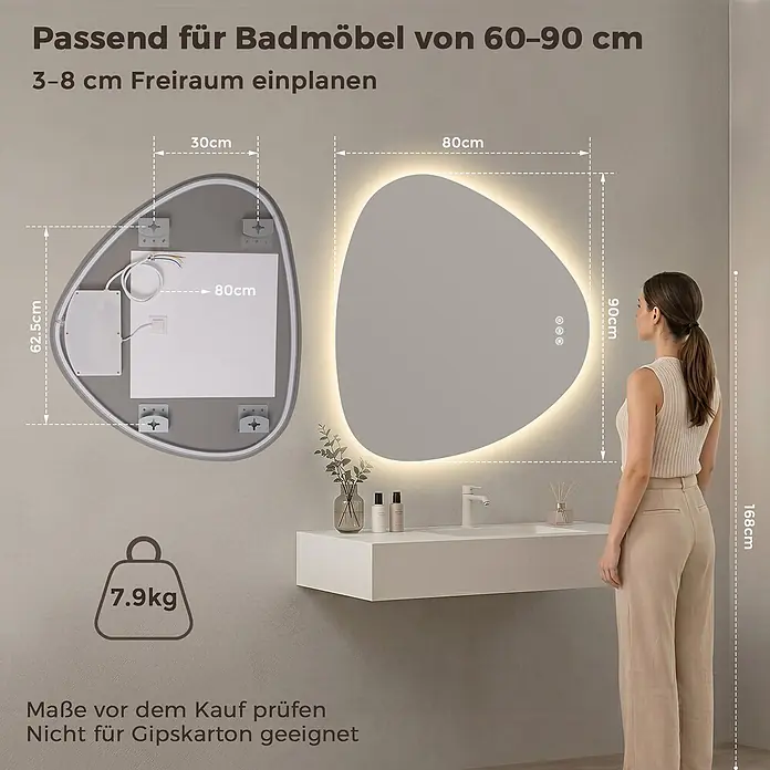 LED Badspiegel dreieckig 80 x 90 cm, 3 Lichtfarben, dimmbar, Memory -  - Beleuchteter, unregelmäßig geformter Badspiegel (80x90cm, 7,9kg) über einem Waschbecken, Person als Größenvergleich.