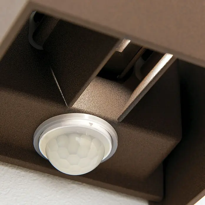 Orion Leuchten LED-Sensor-Außenwandleuchte Cube - 13 W, L x B x H: 10 x 10 x 10 cm, Corten, Klar, Warmweiß - Ein transparenter, kuppelförmiger Bewegungssensor mit Wabenmuster, integriert in eine strukturierte bronzefarbene Leuchte.