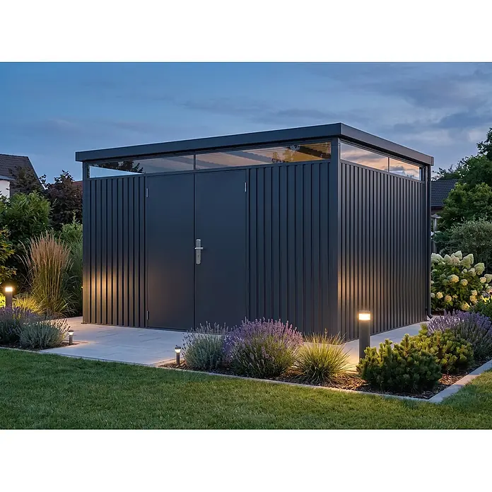 StarLine Metall Gerätehaus Solidum 11,4 m² - Außenbreite inkl. Dachüberstand: 394 cm, Außentiefe inkl. Dachüberstand: 314 cm, Metall, Anthrazit RAL 7016 - Moderner, dunkelgrauer Geräteraum mit vertikaler Metallverkleidung und oberen Glasbereichen, abends von Gartenleuchten beleuchtet.