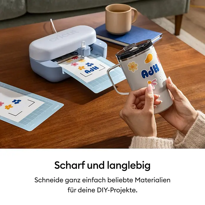Cricut Joy Ersatzklinge Premiumfeinschnittklinge - Passend für: Cricut Joy™, Cricut Joy™ 2 und Cricut Joy Xtra™ - Eine hellblaue und weiße Cricut-Schneidemaschine erstellt bunte Aufkleber, während eine Hand einen auf eine Tasse klebt.