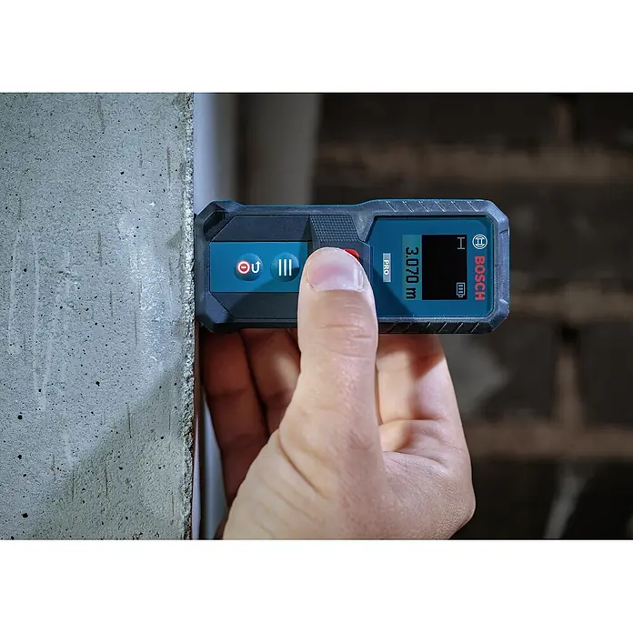Bosch Professional Medidor de distancia láser GLM 50-21 - Gama de medición: 0,15 m - 50 m - Una mano sostiene un medidor láser Bosch azul y negro contra una pared de hormigón, mostrando 3,070 m.