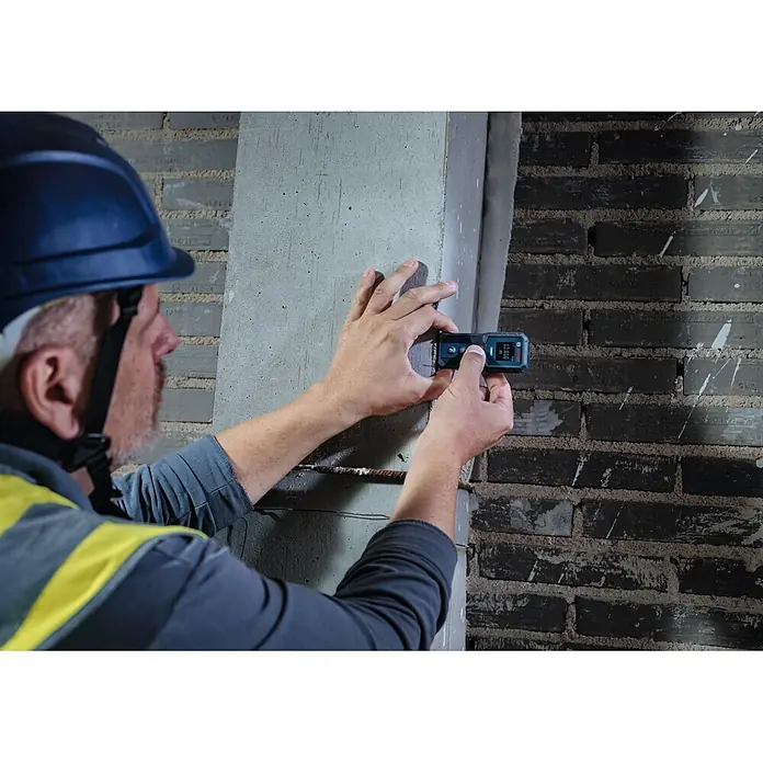 Bosch Professional Medidor de distancia láser GLM 50-21 - Gama de medición: 0,15 m - 50 m - Hombre mide pilar de hormigón con medidor láser Bosch azul/negro, muestra '12.010 m'.