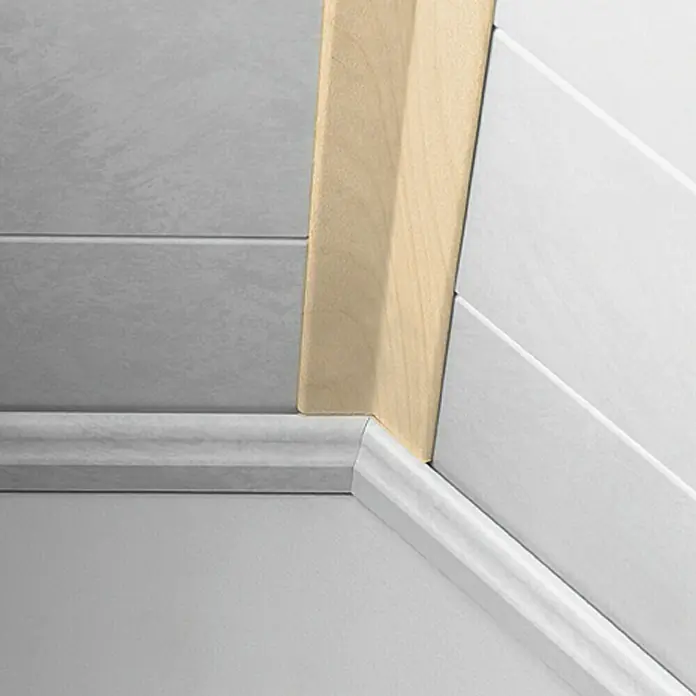 LOGOCLIC Faltleiste Ahorn - 260 cm x 22 mm x 22 mm - Detailaufnahme eines Eckbereichs mit Bodenleisten und Holzverkleidung, das die Übergänge zwischen Wand und Boden hervorhebt.