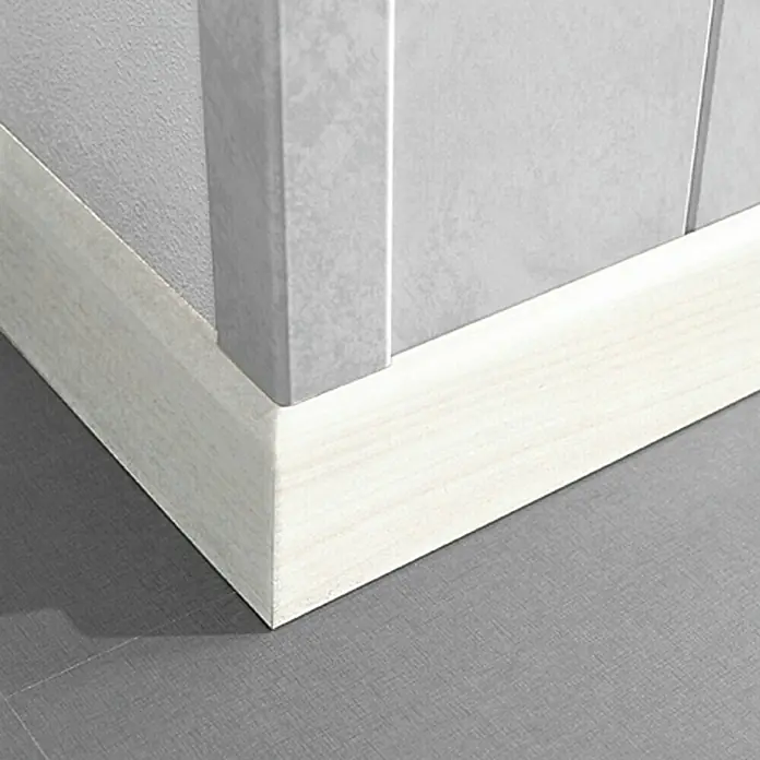 LOGOCLIC Sockelleiste K 58 Birnbaum Weiß - 260 cm x 10 mm x 58 mm, MDF - Detailansicht einer modernen, weißen Fußleiste, die an einer grauen Wand entlangläuft und einen sauberen Übergang zum Boden bildet.