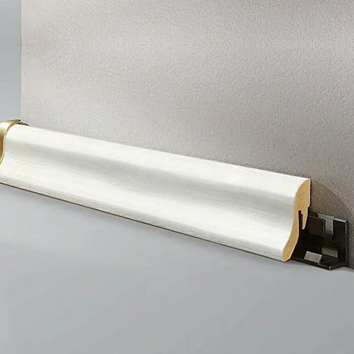 LOGOCLIC Sockelleiste Birne Weiß - 260 cm x 22 mm x 40 mm, MDF - Nahaufnahme einer weißen Fußleiste an einer grauen Wand, die ein sauberes und modernes Designelement im Raum hervorhebt.