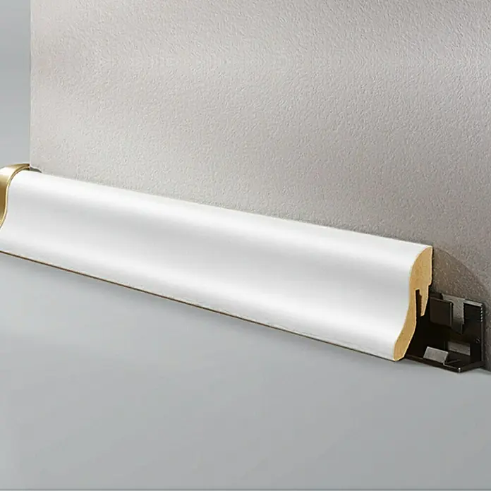 LOGOCLIC Sockelleiste Uni Weiß - 260 cm x 22 mm x 40 mm, MDF - Eine weiße Fußleiste mit goldfarbenen Akzenten vor einer grauen Wand, die ein elegantes und modernes Design für jeden Raum bietet.