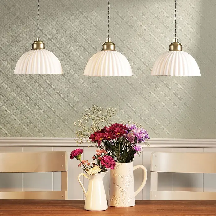 Vliestapete Mr Jones 1000x52cm Laura Ashley -  - Drei weiße gerippte Pendelleuchten mit Messingbeschlägen hängen über einem Esstisch.