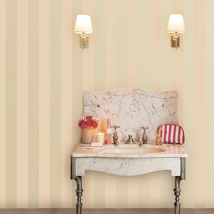 Perlmuttstreifen -  - Eleganter Marmor-Waschtisch mit verzierten Silberbeinen und Armaturen, dekoriert mit Blumen und Toilettenartikeln, in einem gestreiften Raum.
