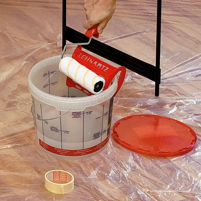 Lehnartz Kleisterroller Roll-On Vlies Plus - Breite Rolle: 180 mm - Nahaufnahme eines Lehnartz Farbrollers, der auf einem Farbeimer platziert ist, mit Abdeckband und Eimerdeckel auf einer Plastikplane.